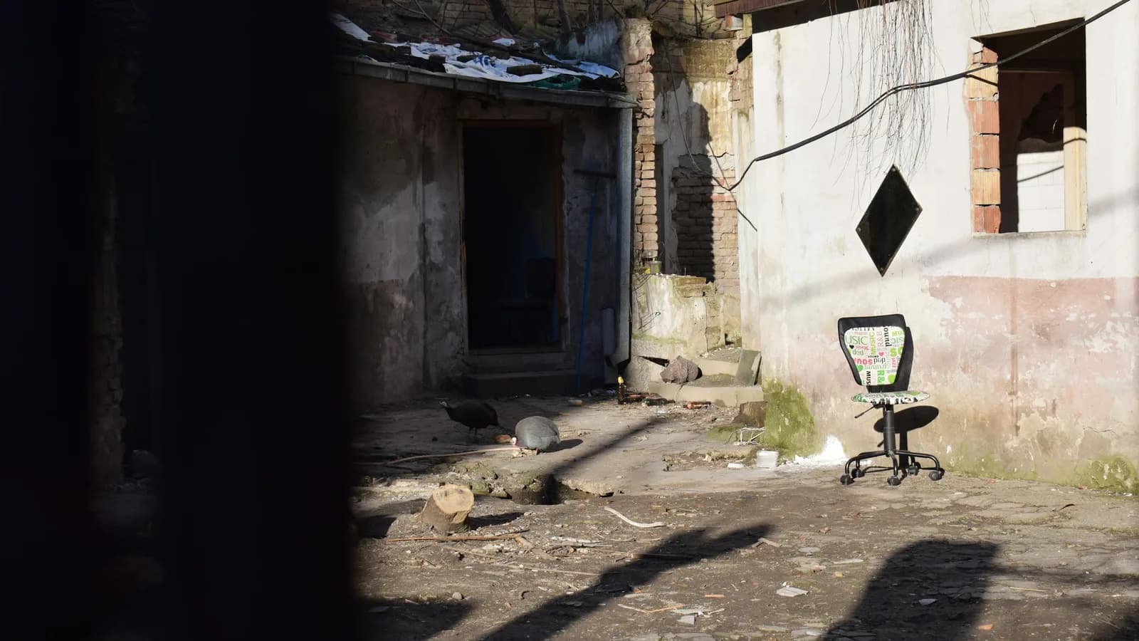 Silla vacía en el interior de un edificio deteriorado, con luz entrando por una ventana.