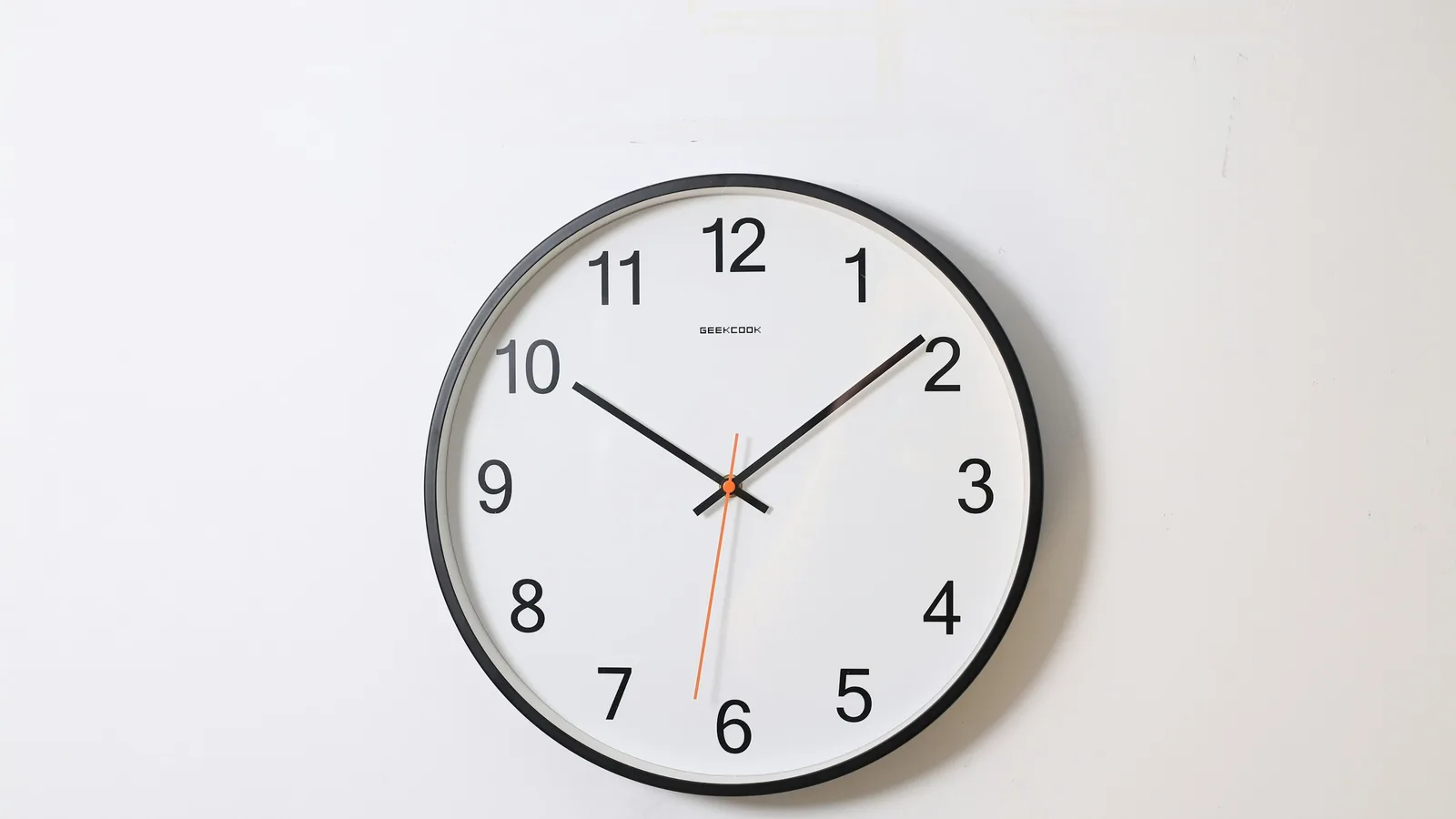 Reloj de pared analógico redondo sobre una pared clara.