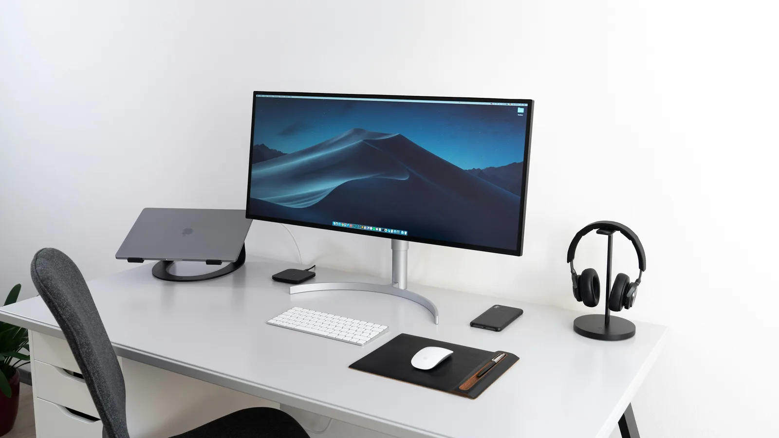 Escritorio ordenado con un monitor ancho, teclado y ratón sobre la mesa.